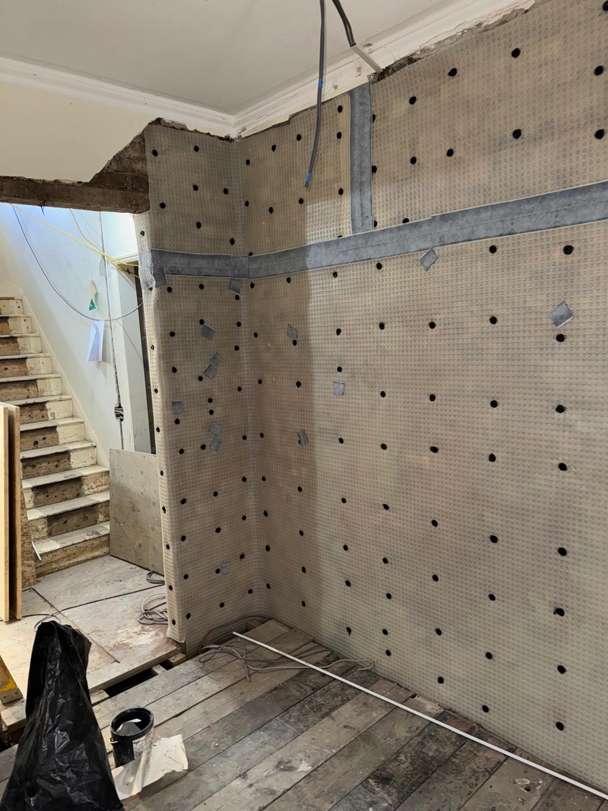 Damp-proofing membrane fixed to internal walls beside a staircase during a strip-out